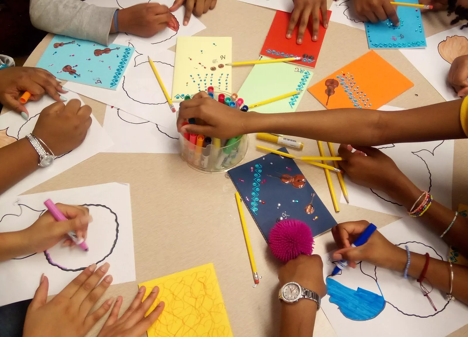 A group of Black students colouring at a big desk.