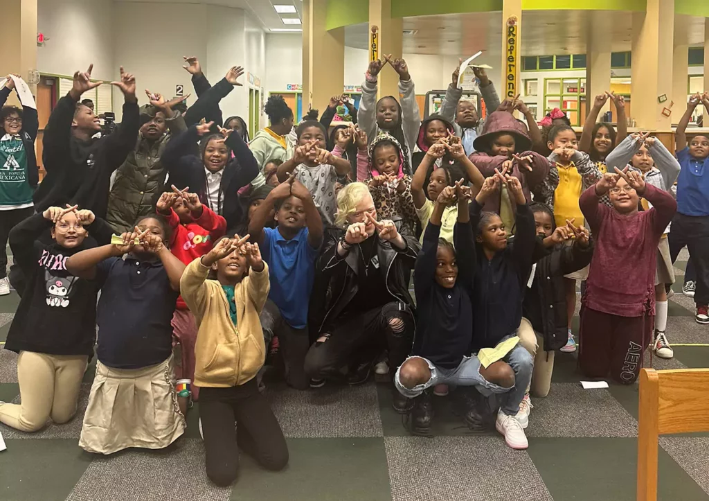 A group of students posing with RobenX. They are all holding their hands in the shape of an X.