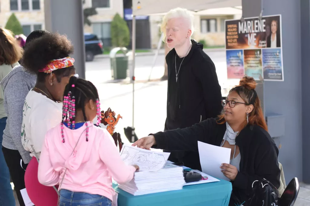 RobenX and Teiyonna Douglas handing out colouring pages from their book, The Colours of Olleh.