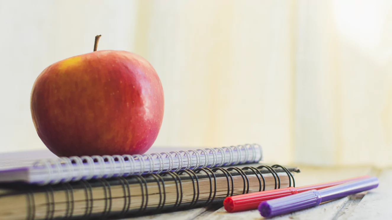 Image of an apple sitting on top of a stack of notebooks.