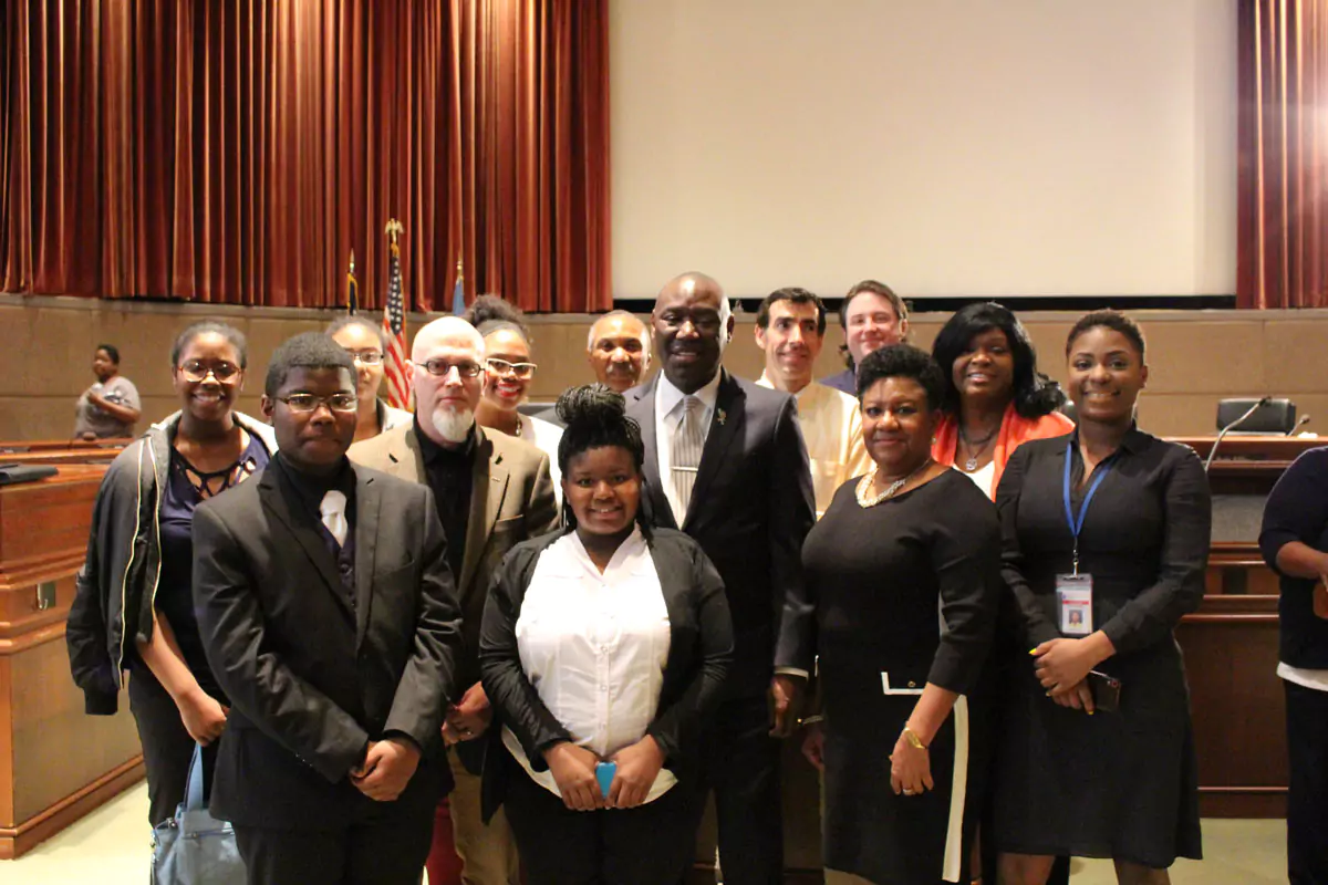 A group of student participants and law professionals posing at the front of a court room.